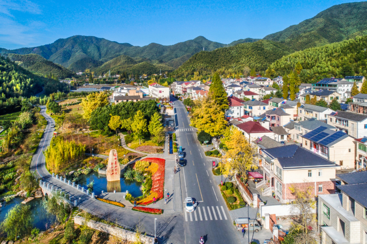 第一視點丨記者再訪余村手記：綠水青山變成幸?？可? /></p>
<p>安吉余村鳥瞰圖</p>
<p><strong>一</strong></p>
<p>歲月流轉。綠色，激蕩著之江大地生態(tài)文明的澎湃動力?；厥讈砺罚?005年8月15日，注定載入史冊的日子。</p>
<p>走進村委會舊址，二樓最西側，那間大約十來平方米的簡陋會議室，居中是一張供十來人坐的圓桌和木椅，兩側各擺放著一排敞開的鋼制折疊椅，這里依然保留著18年前的樣子。</p>
<p>記憶的沙漏宛若潮水瞬間涌出——</p>
<p>那天下午，處在轉型十字路口的余村，迎來了習近平同志。</p>
<p>狹小的會議室里，習近平同志和大家落座交談。</p>
<p>“村里和鎮(zhèn)里基層同志先講，暢所欲言，縣里的同志可以作補充。”習近平同志顧不上擦汗，就讓時任余村黨支部書記鮑新民第一個發(fā)言。</p>
<p>鮑新民沒想到省委書記那么隨和，緊繃的神經(jīng)馬上放松了下來，開始介紹余村民主法治建設，匯報余村經(jīng)濟發(fā)展情況。</p>
<p>“村里剛剛關了礦山、水泥廠，開始著手復綠復耕。”鮑新民說到此處時，習近平同志馬上關切地詢問：“今后村民收入靠什么？”</p>
<p>經(jīng)濟發(fā)展的疾風吹拂過這片土地，也揚起了滿目的煙塵。曾經(jīng)的余村，有多富就有多痛。</p>
<p>上世紀七八十年代起，余村人開礦采石、辦水泥廠，腰包鼓了，但空氣差了、竹林黃了、竹筍小了；村民們不敢開窗、無處晾衣，甚至每天擔心出門采礦的家人可能再也回不來……</p>
<p>“以前一年好幾百萬元的村集體經(jīng)濟收入就只剩下20來萬元，村里老百姓也無處打工了。”鮑新民聲音低了些，顯得有些彷徨，“我們也在想辦法，村里有幾戶人家也辦了農(nóng)家樂，收入還不錯，看來以后要靠生態(tài)旅游、農(nóng)家樂，靠著青山吃青山了。”</p>
<p>“這個就是高明之舉。”聽到這里，習近平同志說。</p>
<p>“既然要‘生態(tài)立縣’，總是有所為、有所不為，而不是什么都要。不要以環(huán)境為代價，去推動經(jīng)濟增長，因為這樣的增長不是發(fā)展。反過來講，為了使我們留下最美好的、最寶貴的，我們也要有所不為，也可能甚至會犧牲一些增長速度，這就是要在經(jīng)濟結構上，舍去一些嚴重污染環(huán)境的高能耗產(chǎn)業(yè)……一定不要再去想走老路，迷戀過去那種發(fā)展模式。”習近平同志即興對在場的同志說了這番話，“綠水青山就是金山銀山。我們過去講既要綠水青山，也要金山銀山，其實綠水青山就是金山銀山。”</p>
<p>綠水青山就是金山銀山！耳目一新又富有哲理。</p>
<p>這話，我寫在了采訪本上，更記在了心里，在之后也深刻影響了浙江乃至中國的發(fā)展。</p>
<p>“不要以環(huán)境為代價”，這是心懷“國之大者”的歷史擔當，也是對經(jīng)濟社會發(fā)展規(guī)律的深邃思考。</p>
<p>9天后，習近平同志在《浙江日報》“之江新語”專欄發(fā)表《綠水青山也是金山銀山》一文指出，“如果能夠把這些生態(tài)環(huán)境優(yōu)勢轉化為生態(tài)農(nóng)業(yè)、生態(tài)工業(yè)、生態(tài)旅游等生態(tài)經(jīng)濟的優(yōu)勢，那么綠水青山也就變成了金山銀山”。</p>
<p>2006年3月，習近平同志又在“之江新語”專欄撰文，闡釋了人們對于綠水青山與金山銀山之間關系的認識的三個階段：第一個階段是用綠水青山去換金山銀山；第二個階段是既要金山銀山，但是也要保住綠水青山；第三個階段是認識到綠水青山可以源源不斷地帶來金山銀山，綠水青山本身就是金山銀山。</p>
<p>走什么樣的發(fā)展路子？追求怎么樣的發(fā)展？</p>
<p>經(jīng)濟發(fā)展與環(huán)境保護統(tǒng)一，生態(tài)優(yōu)勢向經(jīng)濟優(yōu)勢轉化，一次次深入淺出的闡釋，講清了道理，指明了方向。</p>
<p style=